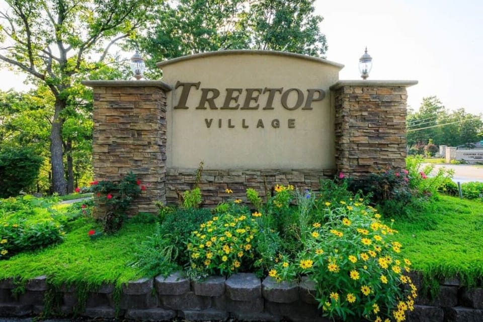 This inviting entrance to Treetop Village welcomes you with a beautifully landscaped monument sign, featuring charming stone pillars and lush greenery.