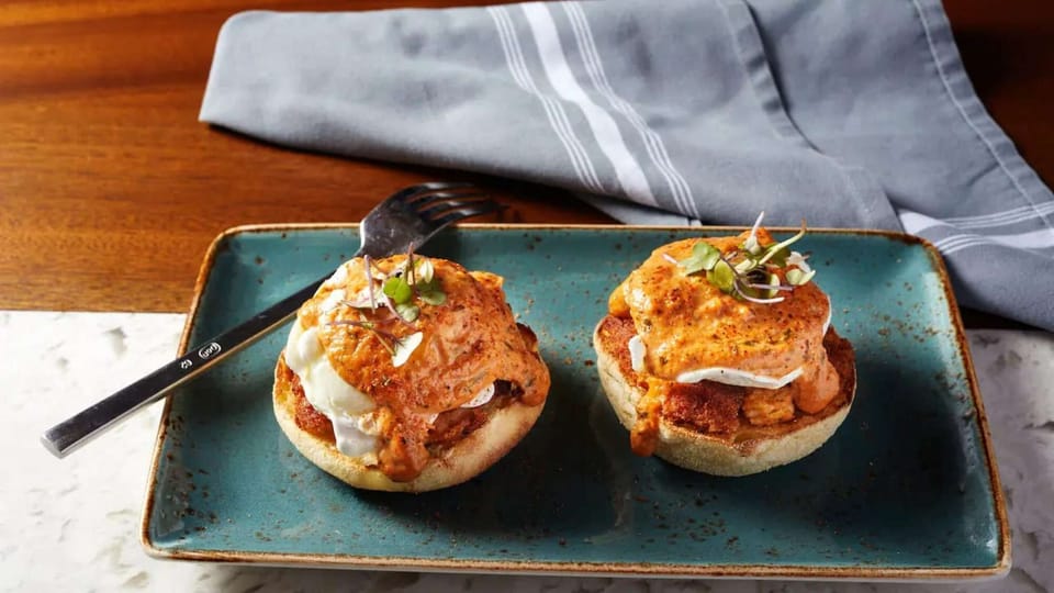 Eggs Benedict with spicy sauce on toasted English muffins