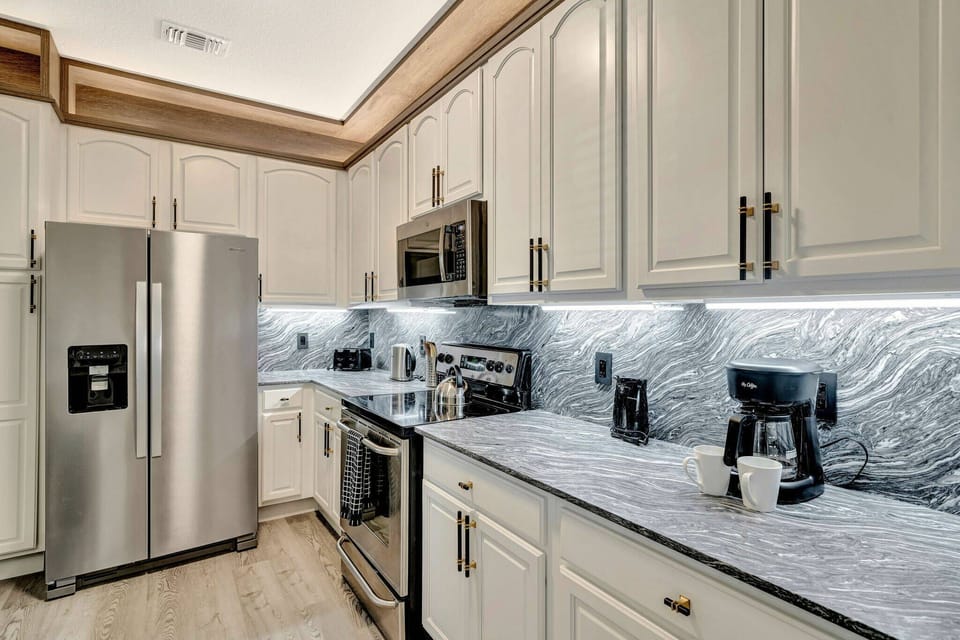 Enjoy a stylish kitchen featuring stainless steel appliances and a stunning marble backsplash. With ample cabinetry and under-cabinet lighting, this space combines functionality and sophistication for all your culinary adventures.