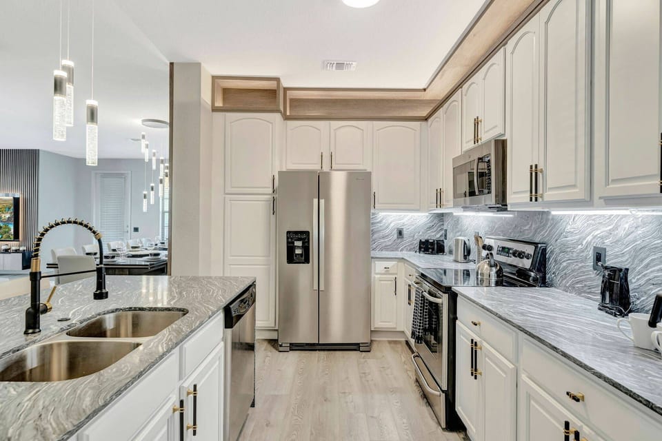 Discover a beautifully designed kitchen featuring sleek stainless steel appliances and elegant marble countertops. The soft lighting accentuates custom cabinetry, creating an inviting space perfect for your culinary adventures.