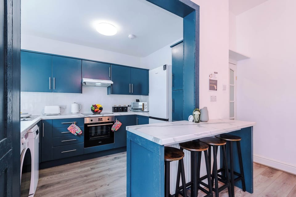 Sleek blue cabinetry meets crisp white finishes in this modern kitchen. With a breakfast bar, stainless appliances, and warm wood accents, it’s a stylish hub designed for cooking, gathering, and enjoying everyday comfort.