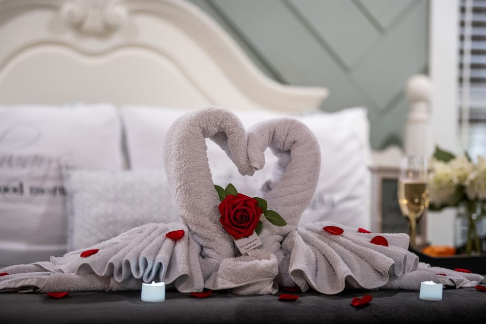 Romance is in the details—swan towels, candlelight, and a single red rose set the scene.