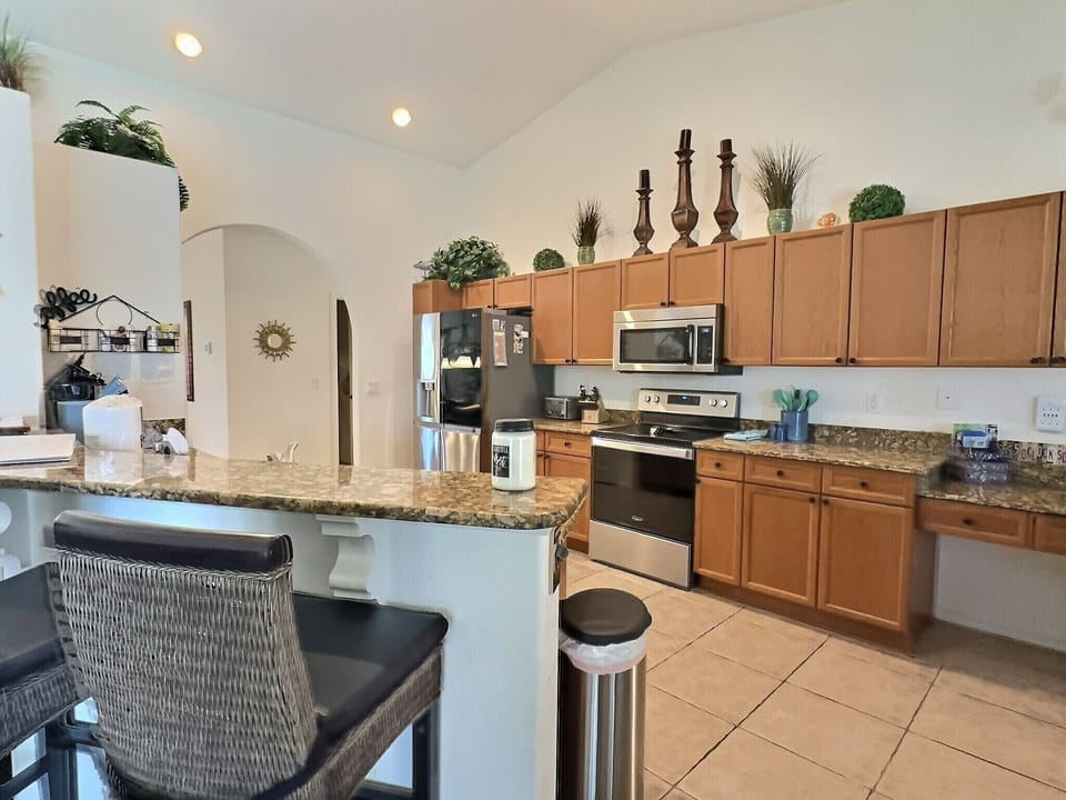 Kitchen featuring a large granite island with bar stools, wood cabinetry, and stainless steel appliances