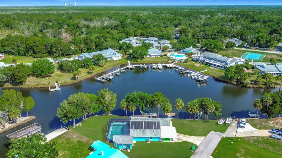 Ariel view of the home with large pool enclosure and yard.   