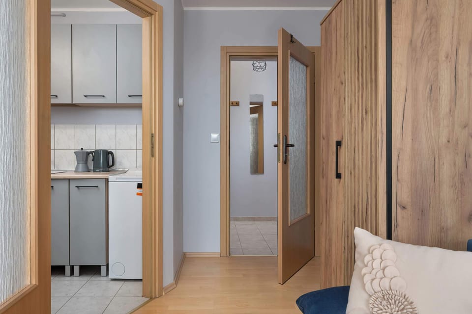 A view of the apartment entrance with wooden doors and a small hallway leading to other rooms.