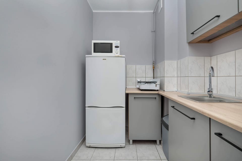 A tidy kitchen featuring white cabinetry, a stove, a microwave, and a refrigerator. 