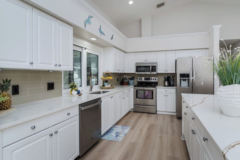 Step into this bright, coastal-inspired kitchen where you'll love preparing meals with modern stainless steel appliances and plenty of counter space. The cheerful nautical touches will make you feel like you're cooking by the sea.