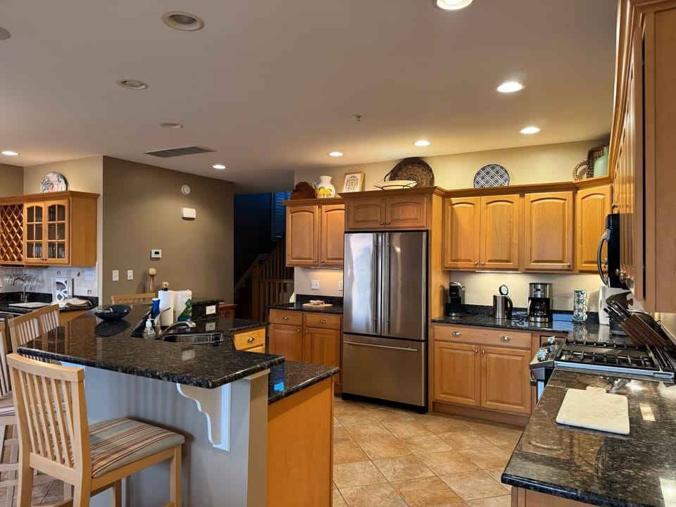 gourmet kitchen with granite countertops, 5 bar stools, and stainless appliances