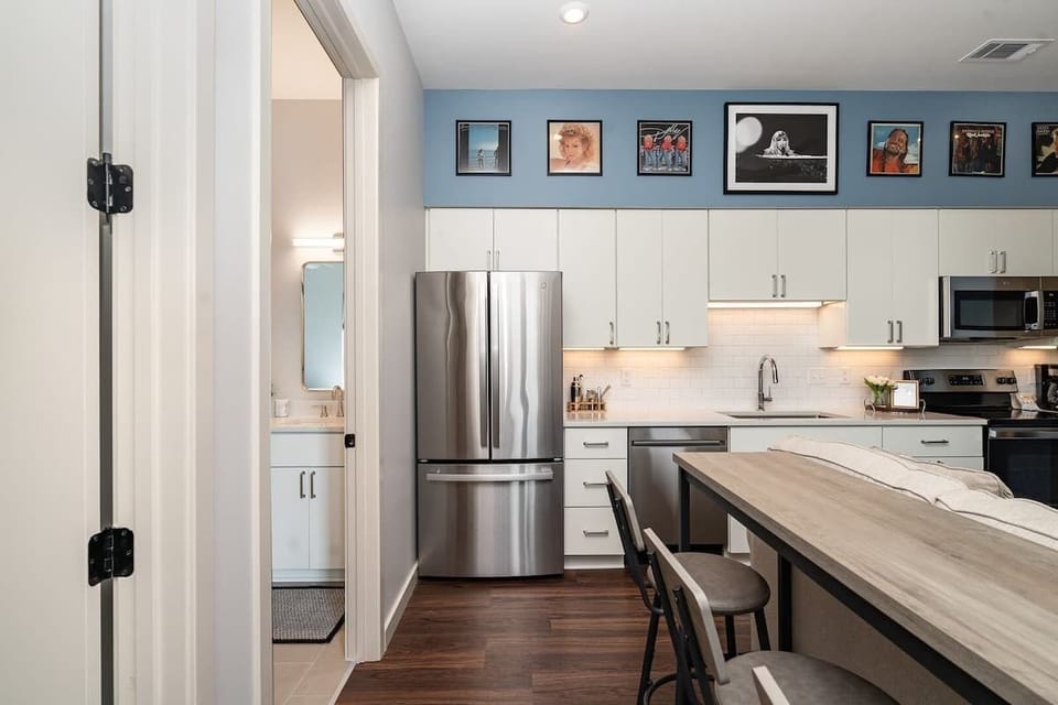Open floor, fully equipped kitchen featuring stainless steel appliances and a dining table offering breakfast bar seating for 3 guests.