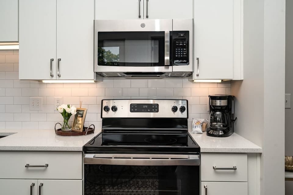 Open floor, fully equipped kitchen featuring stainless steel appliances and a dining table offering breakfast bar seating for 3 guests.