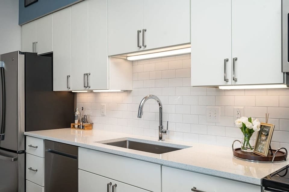 Open floor, fully equipped kitchen featuring stainless steel appliances and a dining table offering breakfast bar seating for 3 guests.