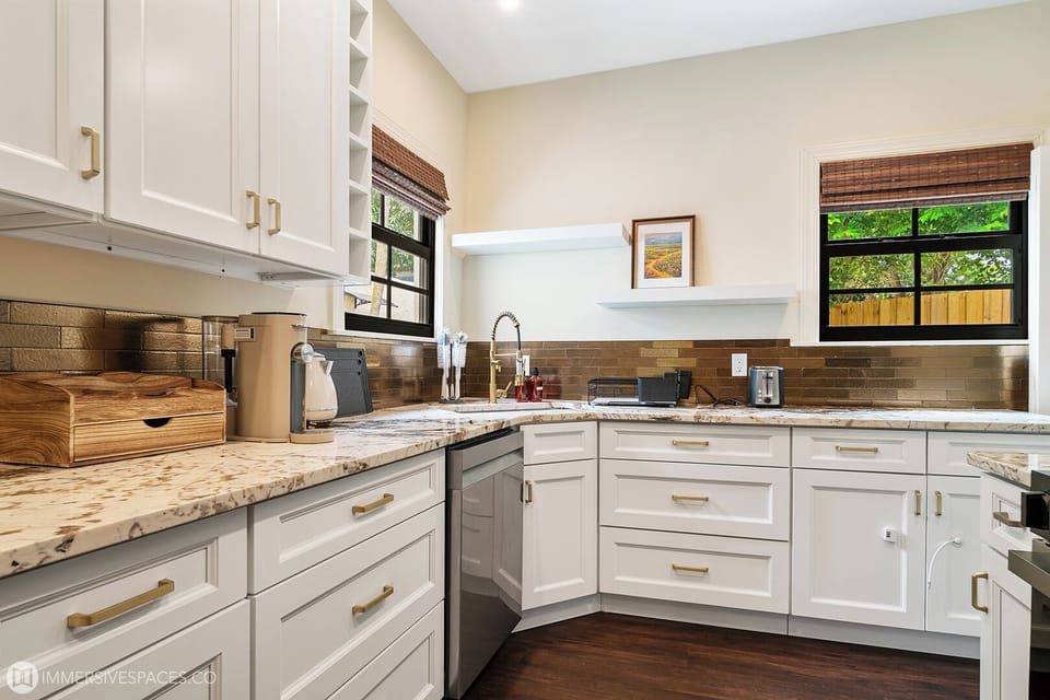 A bright and fully equipped kitchen with modern white cabinetry, ample counter space, and stainless steel appliances for all your culinary needs.
