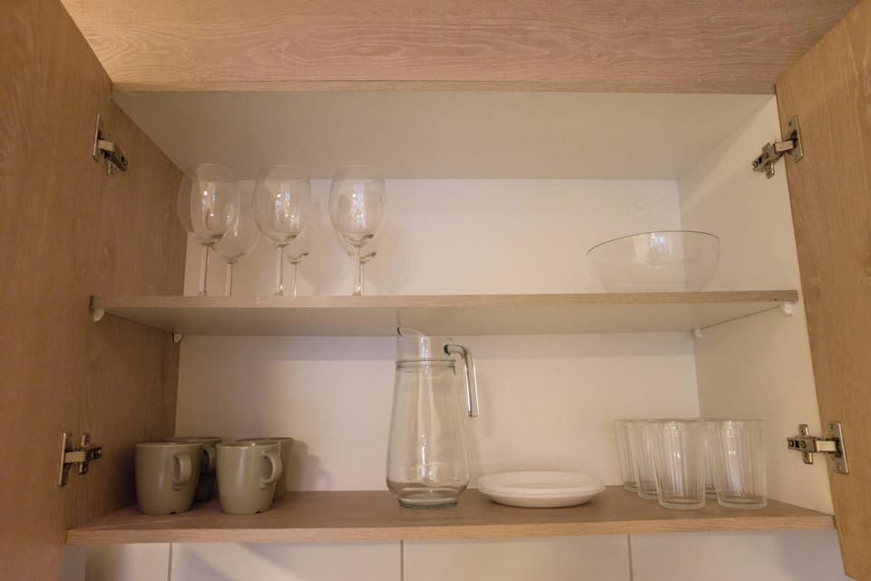 Well-equipped kitchen cabinet with glassware and essentials for a comfortable stay.