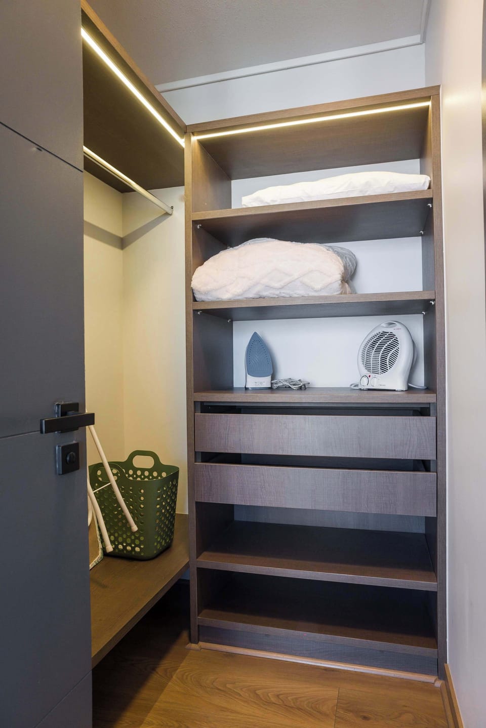 Organized closet with essentials for a comfortable stay, including an iron and extra linens.