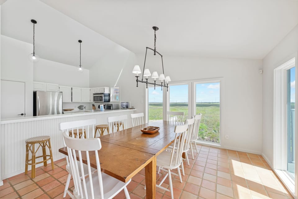 Your bright kitchen flows seamlessly into the dining area, where you'll gather around the rustic farmhouse table while panoramic windows frame endless countryside views.