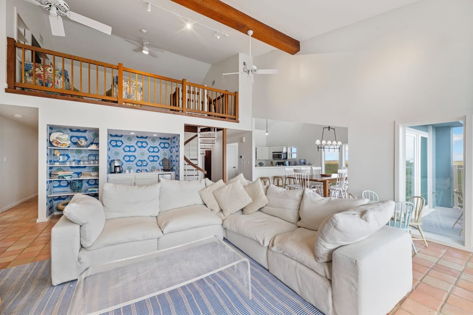 Relax in your spacious living area with soaring ceilings, exposed beams, and a cozy loft overlooking the open-concept design.