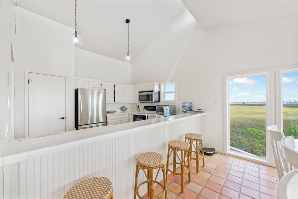 Gather around your bright breakfast bar while natural light pours through windows showcasing peaceful marsh views.