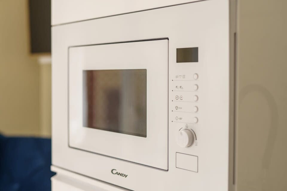 A sleek stainless steel microwave showcases a glowing digital display and a slightly ajar door revealing a clean interior with a rotating glass plate. Its modern design adds a stylish touch to the kitchen.