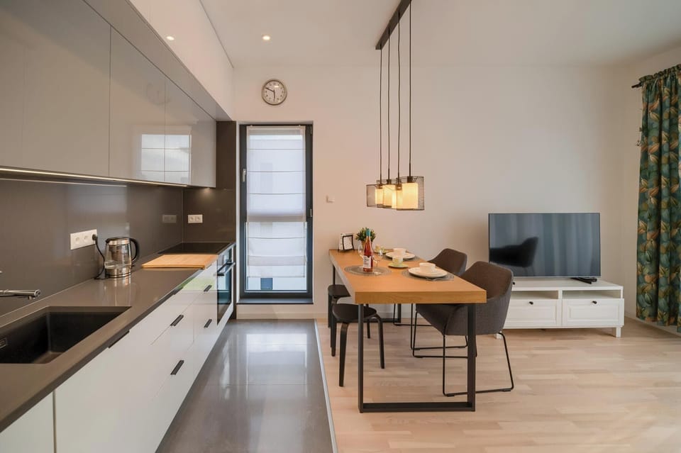 A sleek kitchen with a cabinets, and a dining area in the back.