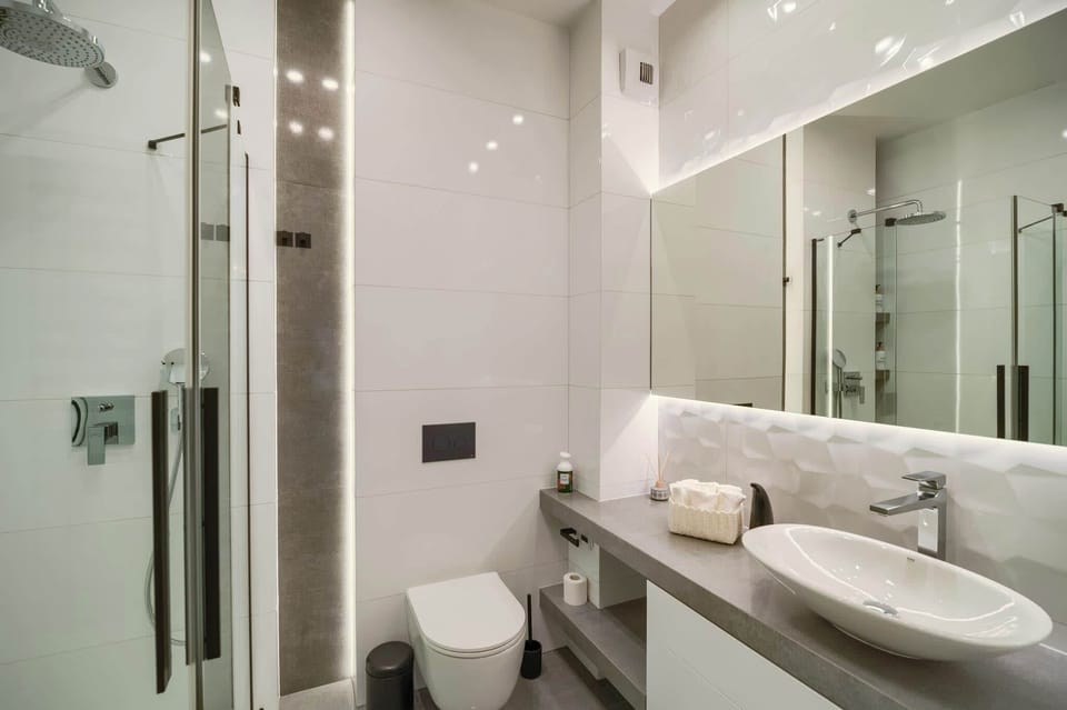 A bathroom with glass shower, white fixtures, and a modern sink area. 
