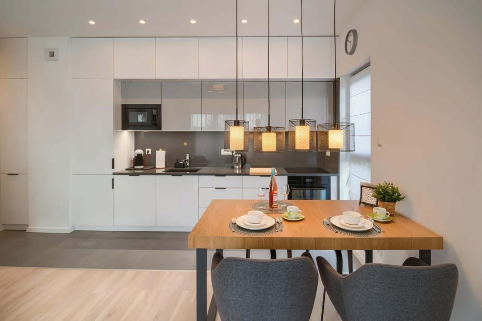 A modern kitchen with sleek cabinetry and a dining area. The lighting is warm and adds a welcoming ambiance.