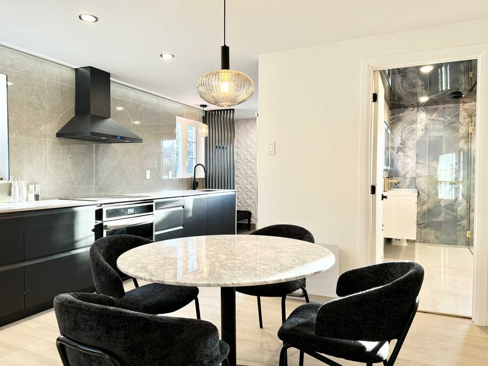 Espace repas chic à aire ouverte avec une table ronde à plateau de marbre et un éclairage suspendu moderne. Le mélange parfait de style et de fonctionnalité.