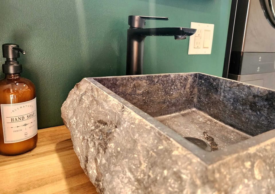 Oasis de salle de bain : vivez le luxe absolu avec un superbe lavabo en pierre et des accessoires noirs au design moderne.
