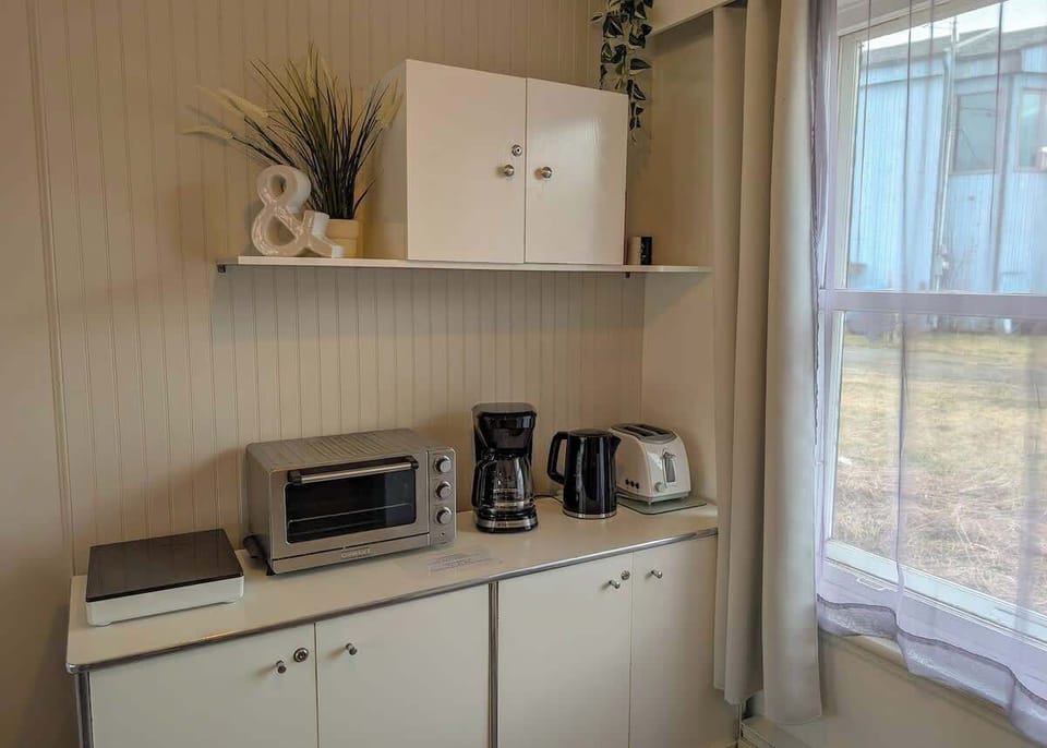 Kitchenette lumineuse avec grille-pain et cafetière, baignée de lumière naturelle — le coin idéal pour bien démarrer la journée.