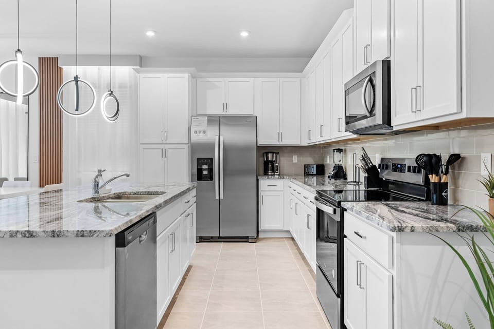 Bright and functional, this kitchen features sleek white cabinetry and elegant granite countertops that create a welcoming atmosphere. The modern appliances and polished finishes invite you to cook and enjoy meals in style.