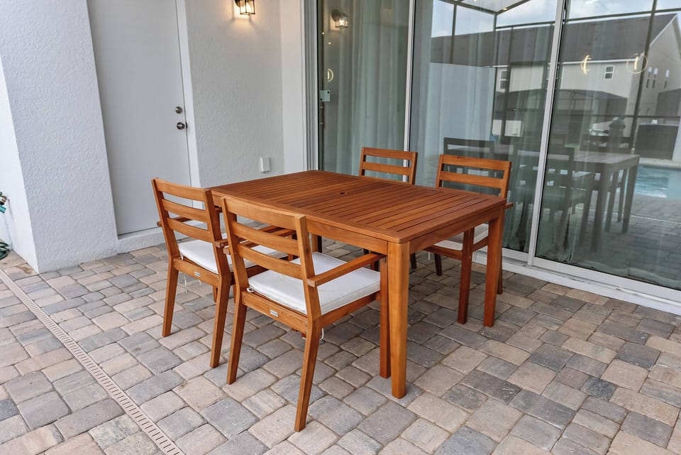 Enjoy al fresco dining at our beautiful wooden table, surrounded by stylish chairs and smooth pavers. The large sliding doors invite natural light, creating a seamless connection to the outdoors for your perfect meal.