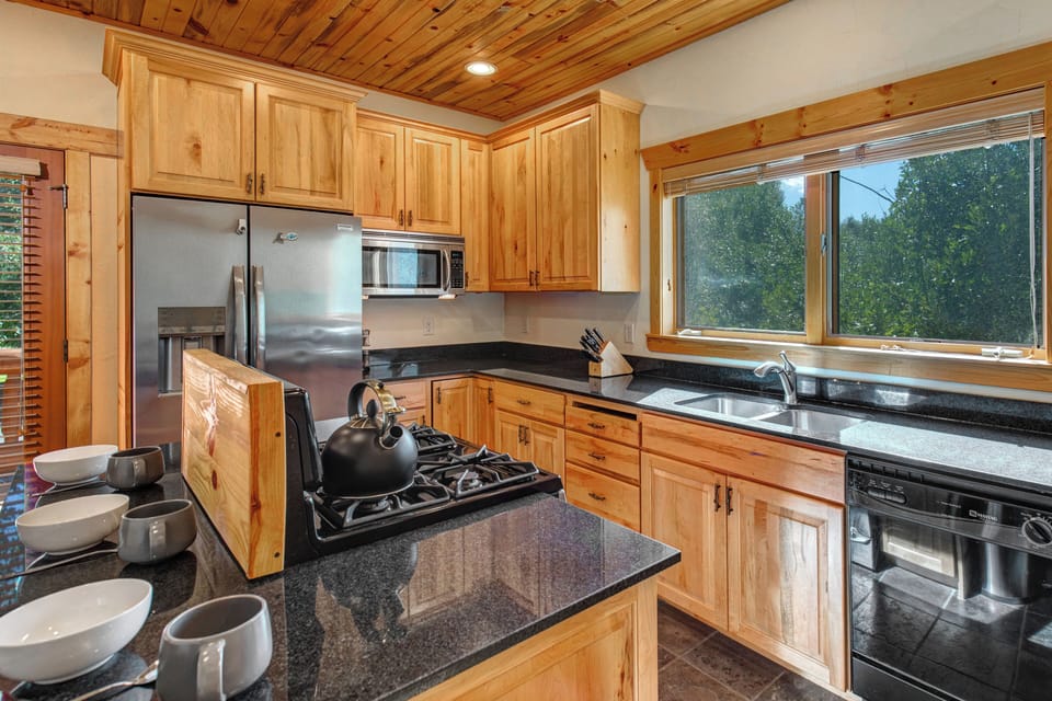 The well equipped kitchen has stainless appliances, black granite counters, and wood cabinets.