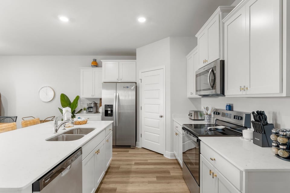 Step into your beautifully appointed kitchen featuring crisp white cabinetry, stainless steel appliances, and gleaming quartz countertops perfect for preparing memorable meals.