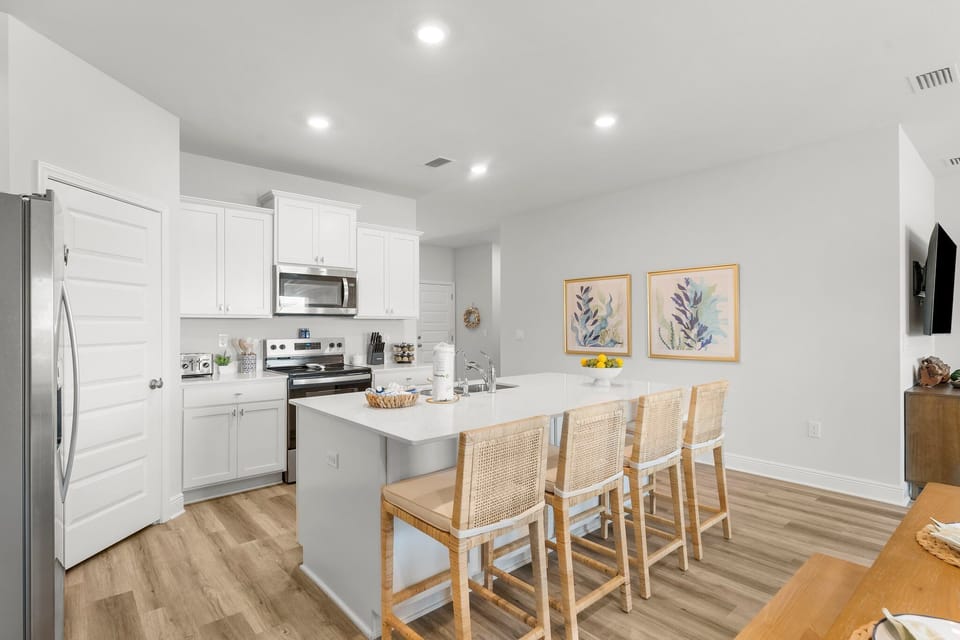 Your modern kitchen features sleek white cabinets, stainless steel appliances, and a spacious island where you can gather for meals or morning coffee.