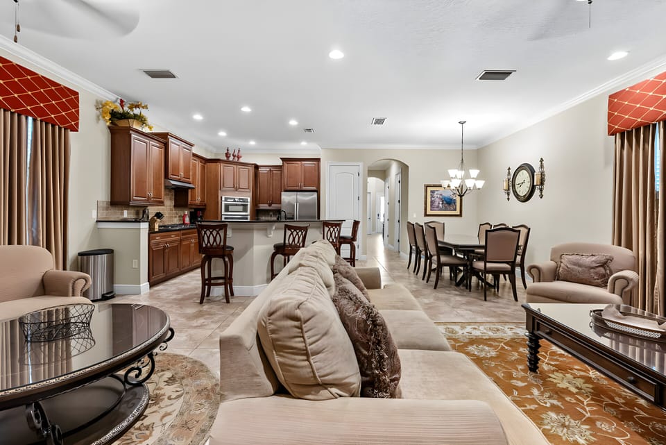 Enjoy a warm, spacious living area featuring rich wooden cabinetry and soft beige furnishings that invite relaxation. The elegant dining set and tasteful decor create a welcoming atmosphere for unforgettable gatherings.