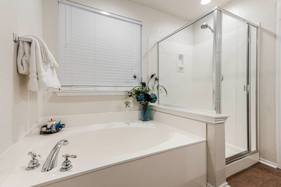 A soaking tub sits next to a glass-enclosed shower stall in the bathroom.