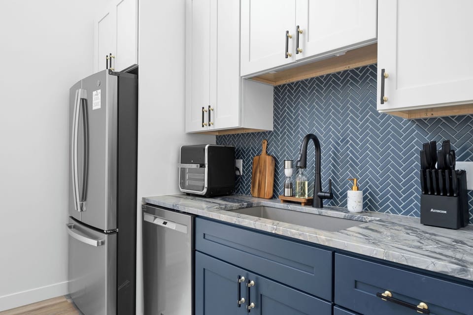 Enjoy cooking in this beautifully designed kitchen with stainless steel appliances, herringbone tile backsplash and modern finishes. Whether you're making breakfast or hosting dinner, this has everything you need for a comfortable stay near Branson, MO. 