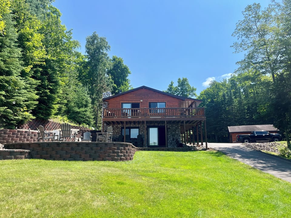 Lake front of house and large patio with fire pit and seating for 10