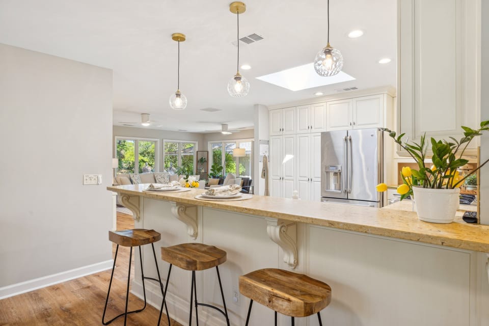 The open layout flows seamlessly into the adjacent dining and living areas, while a breakfast bar with pendant lighting adds charm and everyday convenience.