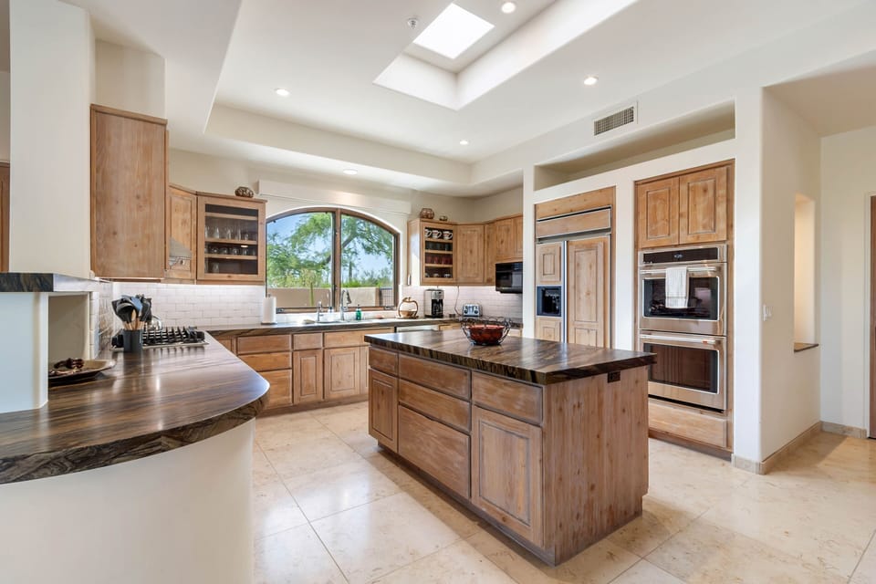 Fully Equipped Kitchen with Double Ovens, Gas Range, Spacious Island, & Counter Open to the Living Area
