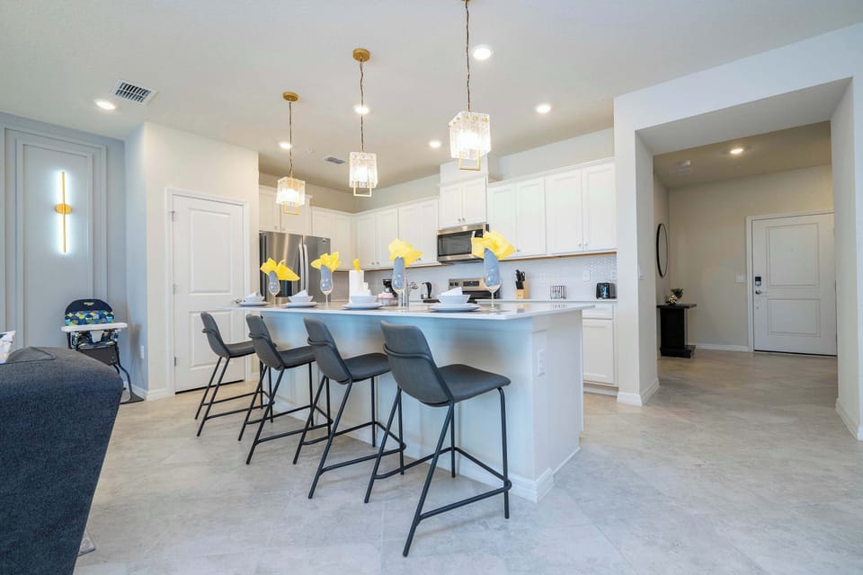 Cook and dine in style in this bright, modern kitchen with a large island, elegant lighting, and seating for the whole group.