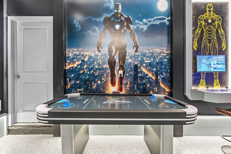 Welcome to our vibrant game room, featuring a sleek air hockey table and stunning artwork, including a striking Iron Man mural. The lively colors and modern design create a perfect backdrop for friendly competition.