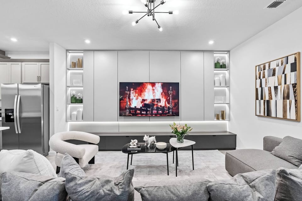 Experience the cozy charm of this stylish living area, featuring soft gray tones, plush seating, and contemporary decor, all enhanced by a sleek media console and modern lighting, making it ideal for relaxation or entertainment.