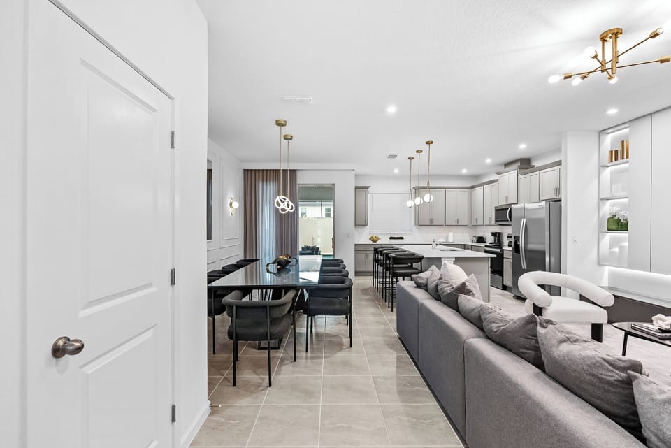 Enjoy a beautifully designed open-concept living area that seamlessly connects to a sleek kitchen with modern cabinetry and stainless steel appliances. Warm lighting creates an inviting dining space, ideal for cozy gatherings.