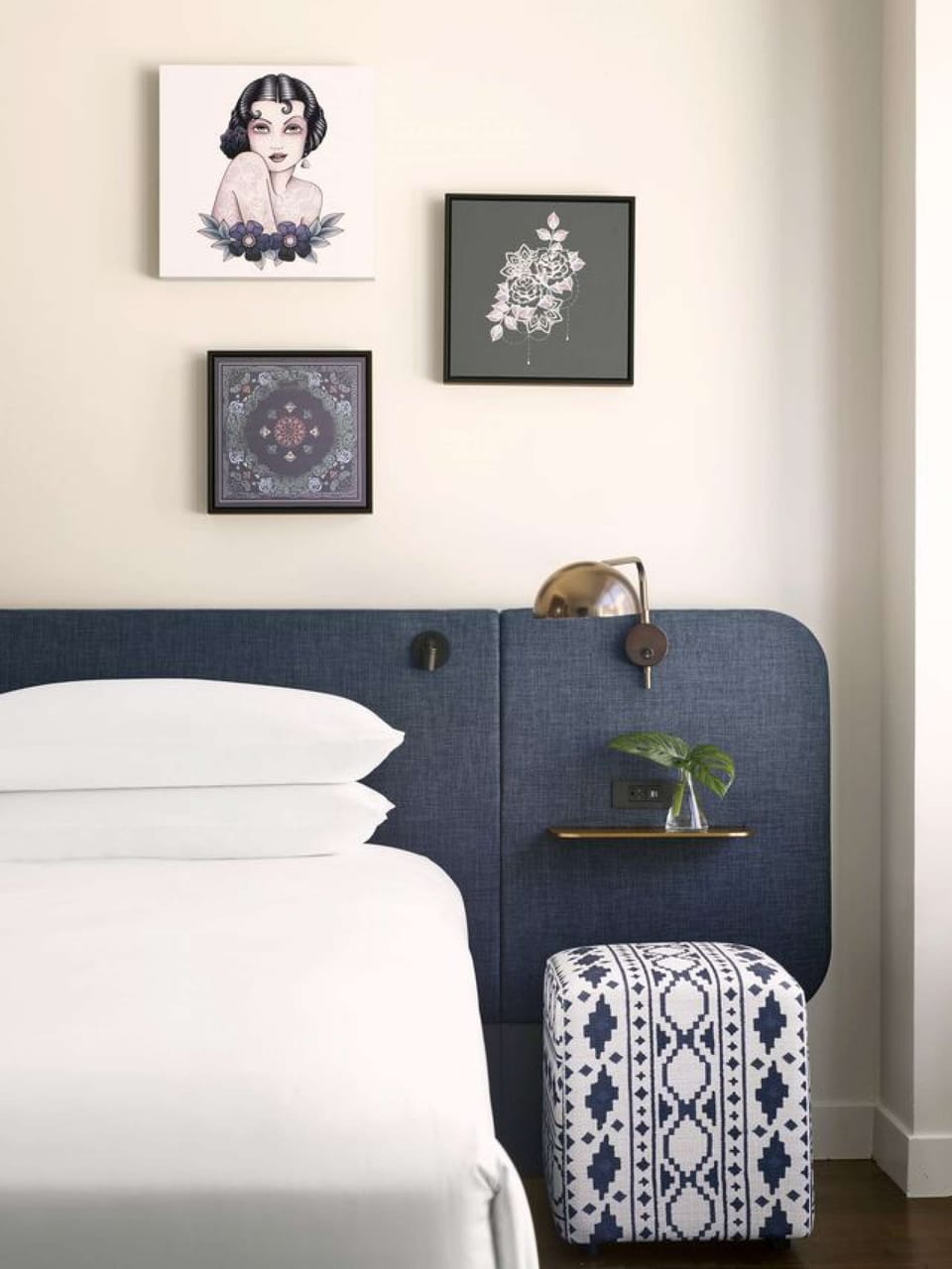 Minimalist bed setup with blue headboard and artistic wall decor