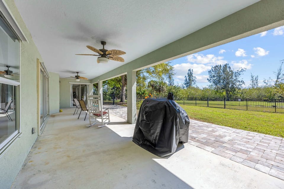 Covered patio with ceiling fans and a view of the fenced backyard.