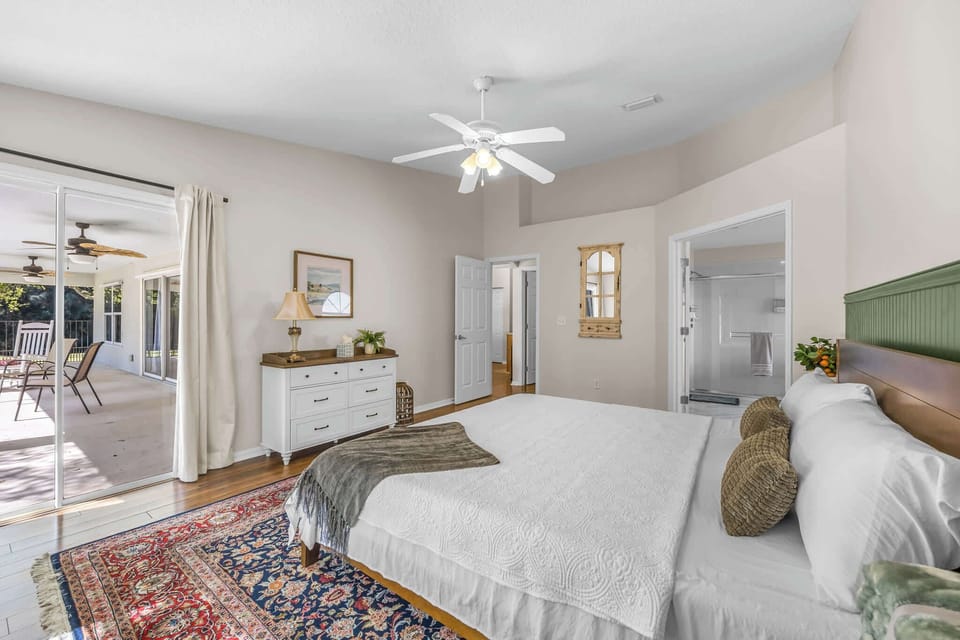 Bright bedroom with sliding doors opening to a covered patio with ceiling fans.
