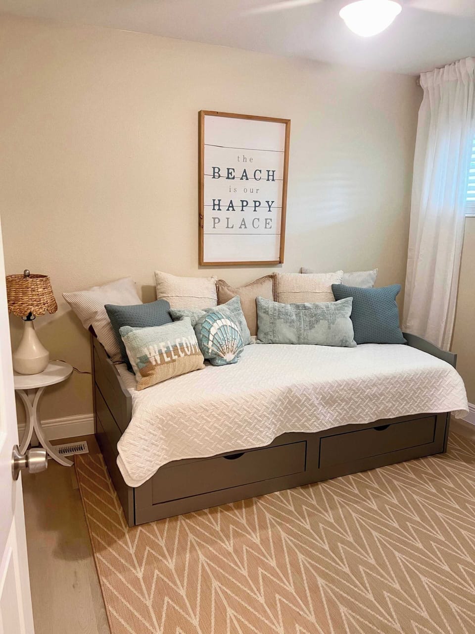 Cozy daybed with beach-themed pillows and wall art for a relaxing stay.