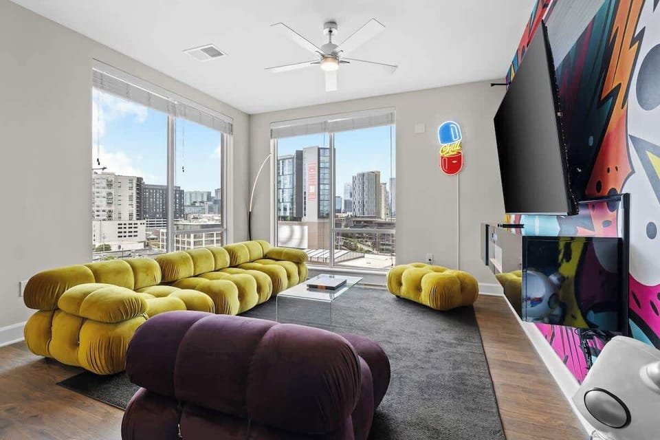 - Spacious living room with city views  
- Modern lounge seating for relaxing stays  
- Vibrant mural adds bold Nashville style  