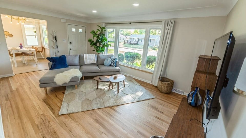 Relaxing sitting room with large bay windows with views of mature trees.