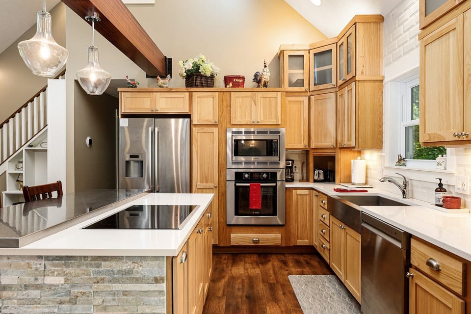 Warm wood kitchen w/ stainless steel appliances, white counters & generous prep space.
